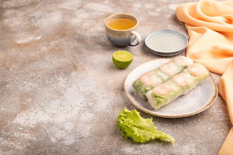 Vietnamese shrimp spring rolls on brown concrete background and orange linen textile. side view, copy space
