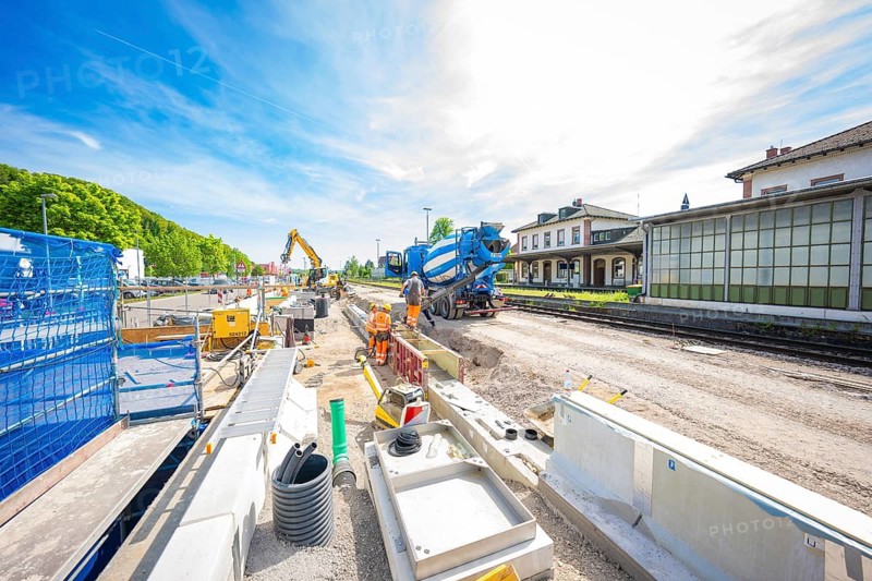 Wide-angle view of a construction site with excavator and building materials under a blue sky, construction site by Leonhard Weiss for the renovation of the railway station and construction of the overhead line, Waldshut, Germany