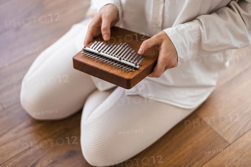 Close-up of hands playing a kalimba, emphasizing the instrument's wooden texture