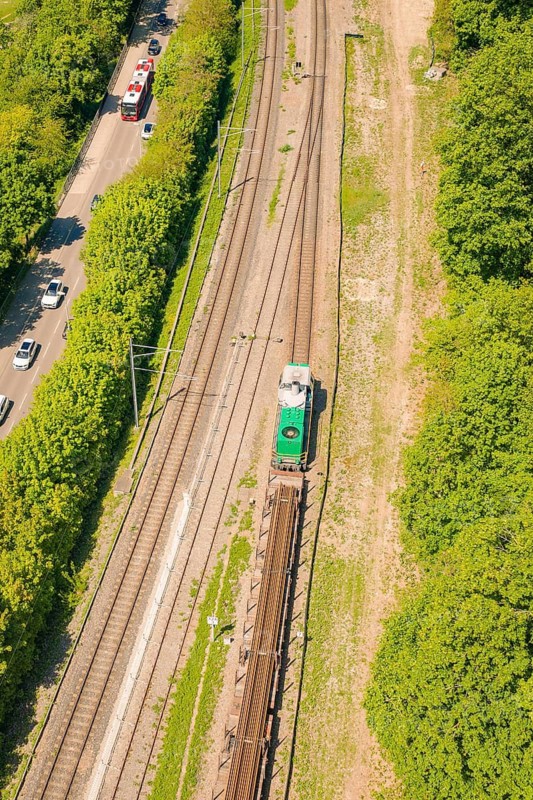 Close-up of a railway line with a passing train, next to it road and vegetation, construction site by Leonhard Weiss to renovate the station and build the overhead line, Waldshut, Germany