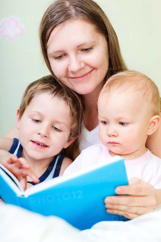A young mother is reading a book, two children, boy and girl, are listening, Finland, Scandinavia