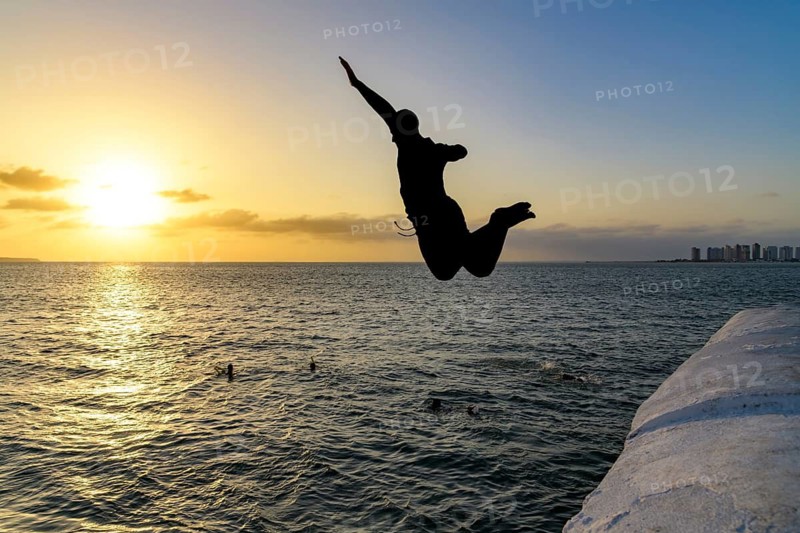 Young person jumping into the sea at sunset in Sao Luis, the capital of Maranhao