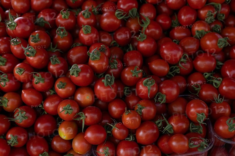 A pile of vibrant red cherry tomatoes with green stems