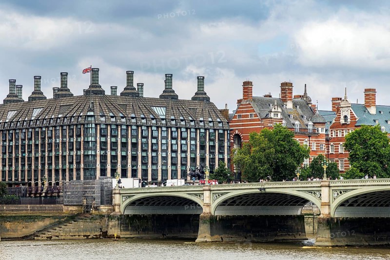 The modern glass and stone facade of Portcullis House, opened in 2001 as parliamentary offices, stands beside the red brick turrets of the Victorian Norman Shaw Building, once part of New Scotland Yard, London, England, United Kingdom