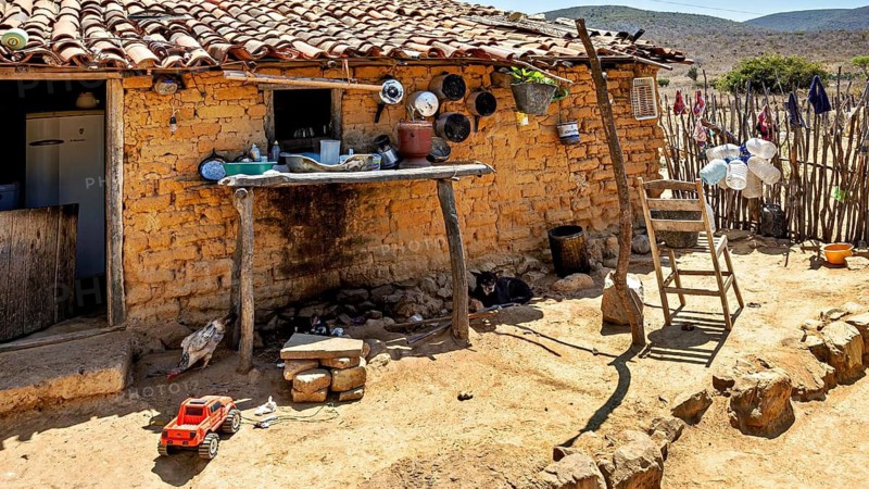 Rustic outdoor kitchen with clay walls and kitchen utensils on one wall, houses in a village in the Caatinga of Bahia in Brazil