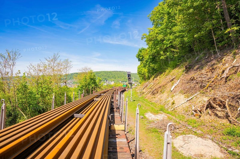 Rails run along a hill with forest under a clear blue sky, Leonhard Weiss construction site to renovate the train station and build the overhead line, Waldshut, Germany