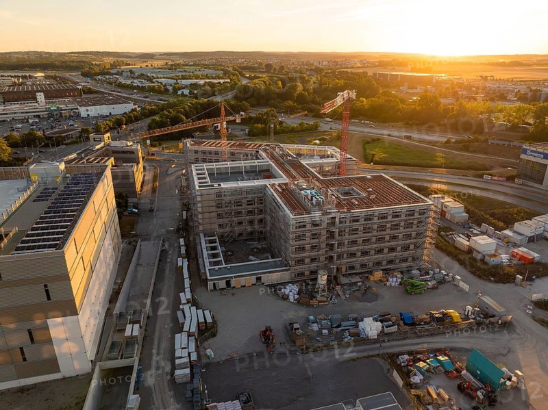 Construction site of a building at sunset, surrounded by cranes and building materials, new hospital building, Böblingen airfield, Germany