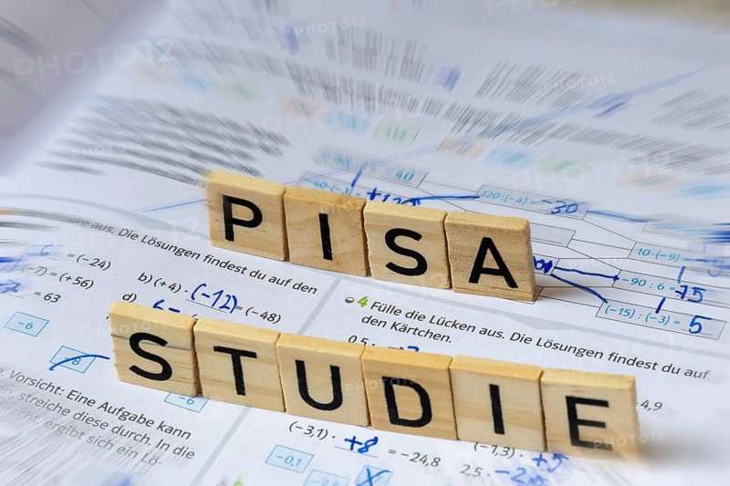 Wooden letters on a math textbook indicate the word PISA STUDY