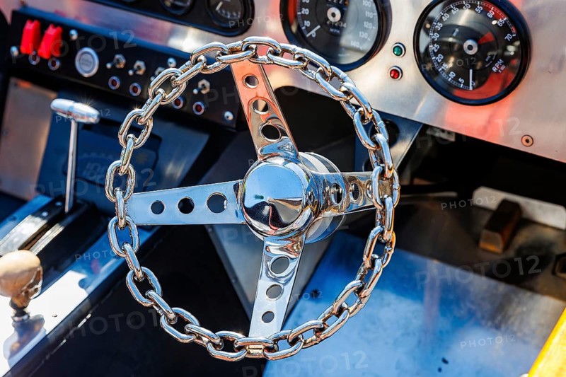 Custom chain-link steering wheel and instrument gauges inside a classic racing car