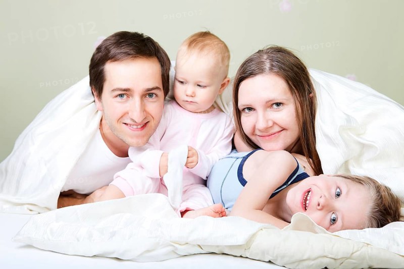 A young happy family, four people relaxing in bed, Finland, Scandinavia