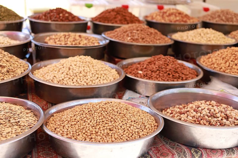 Various seeds and spices displayed in metal bowls at a market, showcasing an array of earthy textures and colors