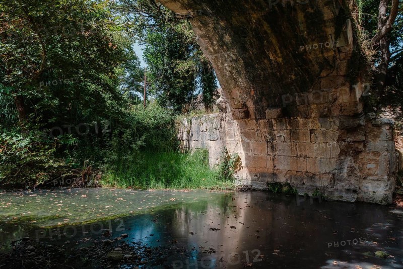 Roman Bridge across the river in Vrises, Crete, Greece, A stone bridge over a calm river surrounded by lush greenery, Crete, Greece