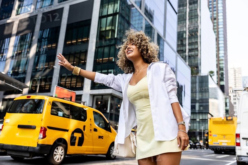 Young woman hailing a yellow cab on an urban street in manhattan, showing modern city transportation, independent travel, and new york lifestyle