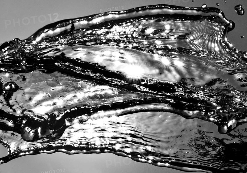 Water frozen by short exposure moving in backlight in front of the sun