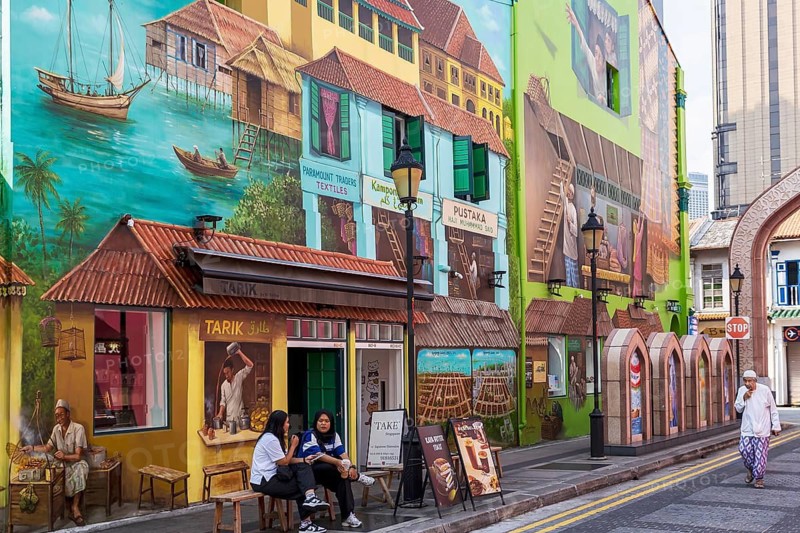 People sitting outside of a cafe by contemporary street art of the Muscat Street Murals, Kampong Glam, Singapore