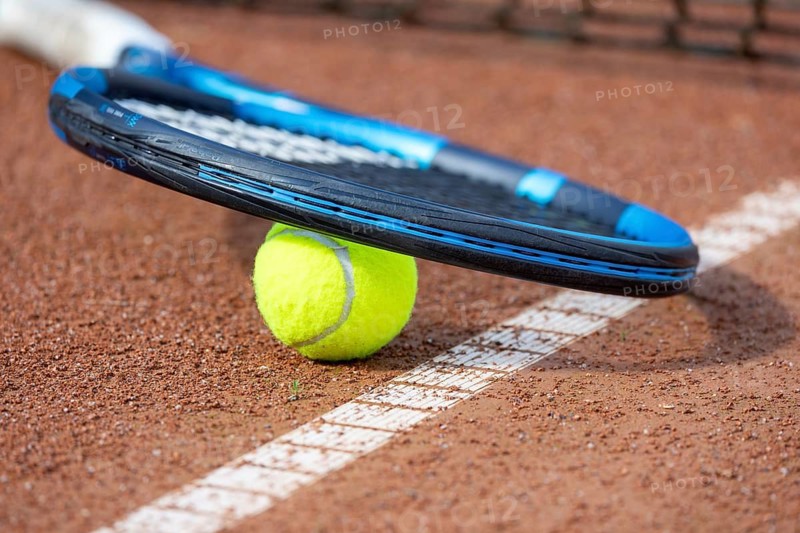 Tennis icon: close-up of a tennis ball and tennis racket on a clay court