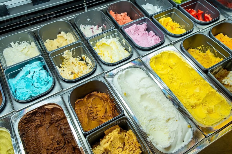 Scoops of colorful gelato and sorbet lined in a display case, showcasing a vibrant assortment of creamy, refreshing frozen desserts for a shop, cafe or artisan counter