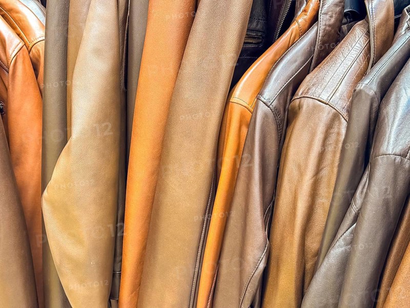 A collection of leather jackets in various shades of brown and tan hanging on a rack. The jackets display different styles and textures, showcasing fashion variety