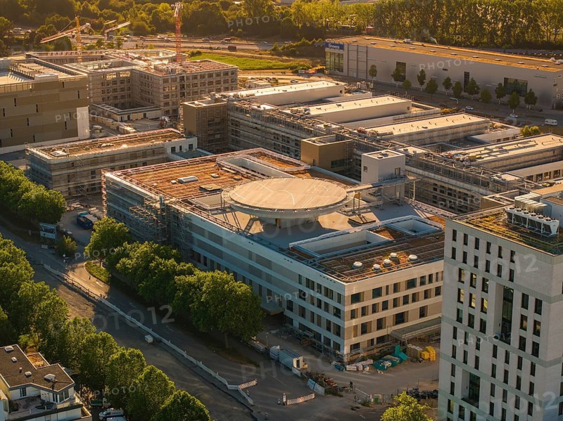 Modern building structures in an industry-like area surrounded by trees, construction site of the new airfield clinic, Böblingen, Germany