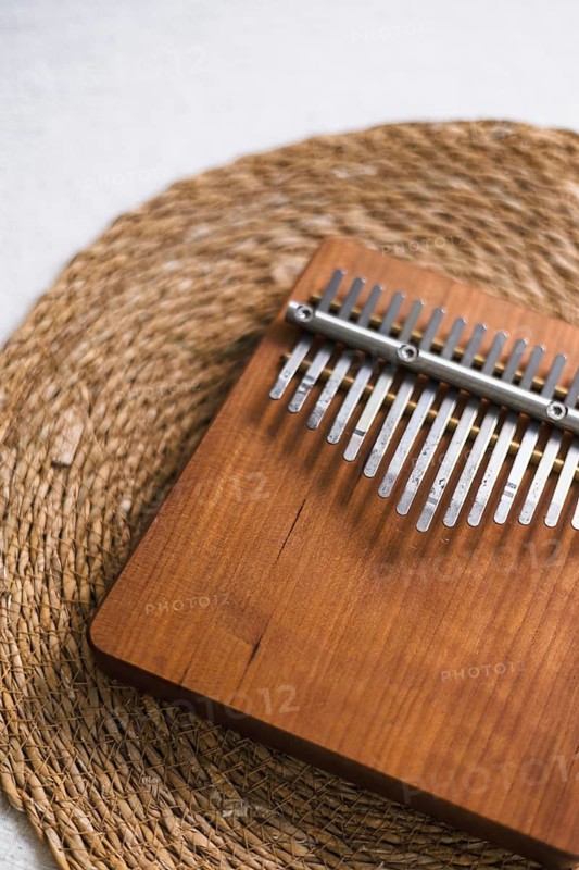 A wooden kalimba with metal tines placed on a woven mat, evoking a rustic feel