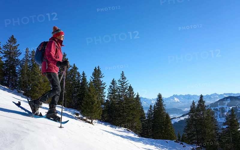 Nice and active senior woman snowshoeing in in the Allgau alps above Immenstadt, Bavaria, Germany