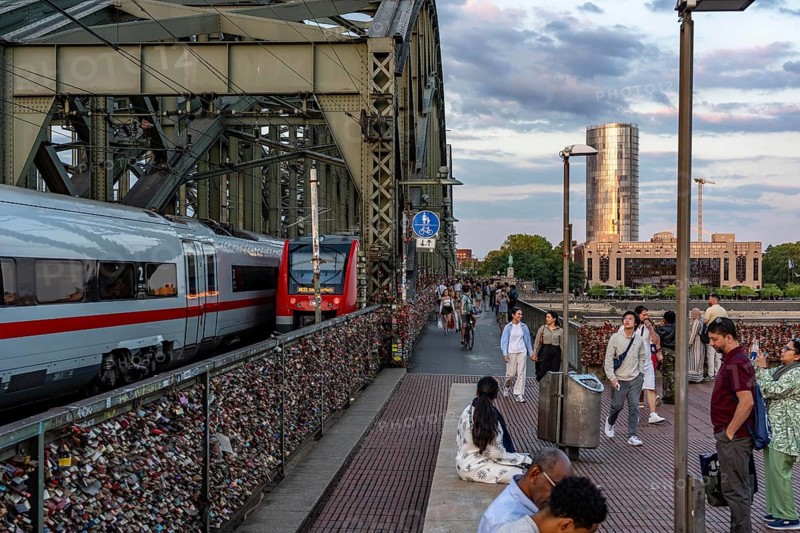 The Hohenzollern Bridge across the Rhine, railroad bridge, people on Kurt-Rossa Square, trains on the bridge, looking east, Deutzer Ufer, KölnTriangle - skyscraper, North Rhine-Westphalia, Germany