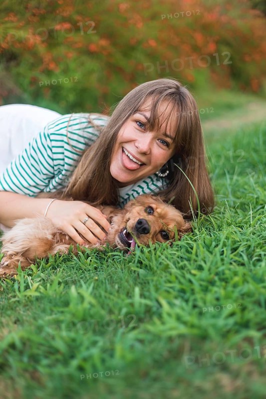 Woman playfully engaging with her dog amidst the grass, exuding joy