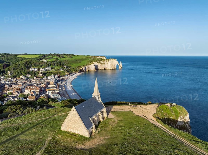 Aerial view of the Notre Dame de la Garde chapel after sunrise at the Falaise d'Amont viewpoint, on the right the coastal town of Étretat with the beach, on the horizon the Porte d'Aval rock formation, Étretat, Alabaster Coast, La Côte d'Albâtre, chalk cliffs, English Channel, Seine-Maritime, Normandy, France