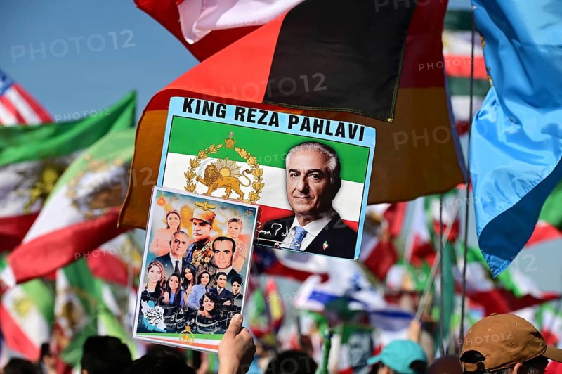 Supporters of Reza Pahlavi demonstrate in front of the Reichstag, including with numerous different flags and posters, which establish Pahlavi's connection to the Shah dynasty and his role as prince and potential future king