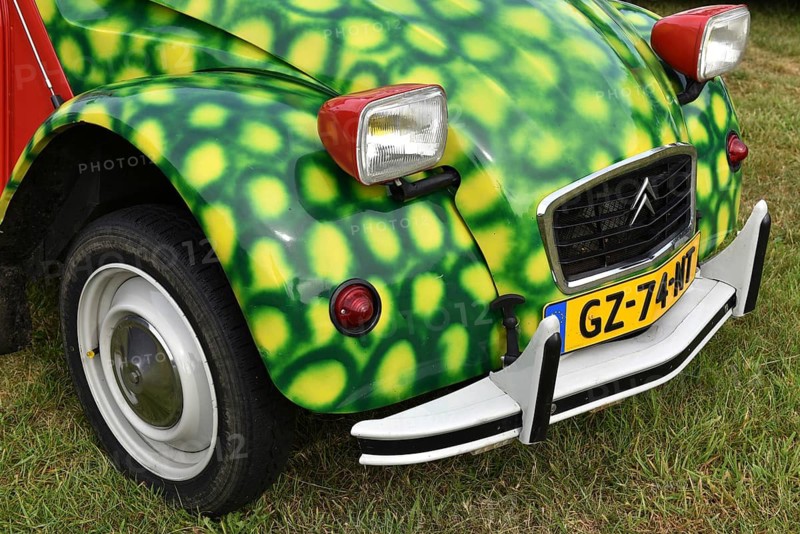 A Citroën 2CV with eye-catching green spot paint parks on grass, vintage Citroën 2CV6 at a duck meeting in Kropp, Schleswig-Holstein, Germany