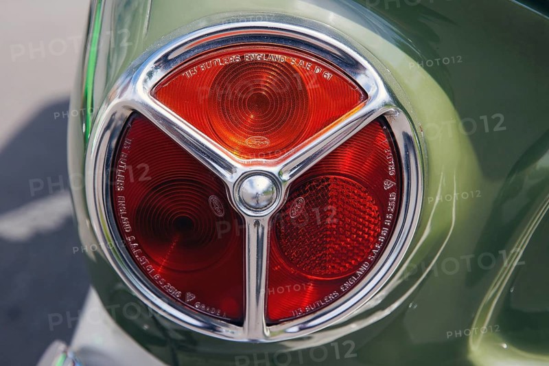 Tri-lobe red tail lamp lens marked Triplex on a green classic car