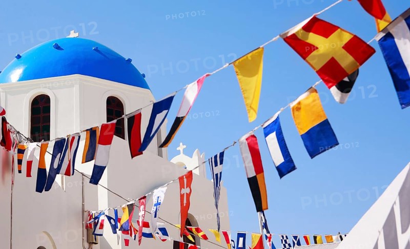 Classic Greek blue dome church and flags in Oia on Santorini, Greece, Santorini island, Aegean Sea, Santorini, Greece