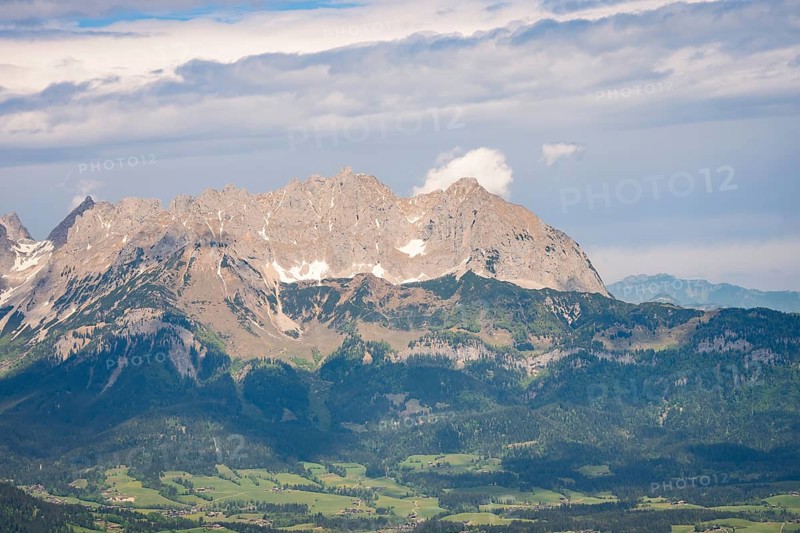 Massive mountain range under dramatic cloud formations and dense forest, Hahnenkamm, Kitzbühel, Austria