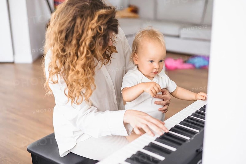 Mother and child focusing on piano keys in a cozy home setting