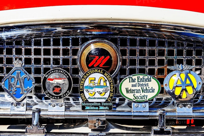 Owners club badges including the RAC and AA mounted on the chrome grille of a vintage car