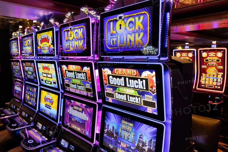 Rows of illuminated slot machines with colorful neon displays on a casino gaming floor, vibrant entertainment and gambling interior at night