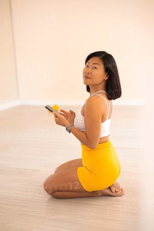 Side view of a woman kneeling while looking at her phone in a minimal space