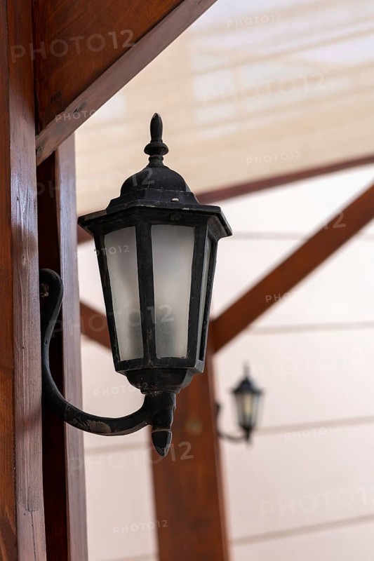 A vintage-style wall lantern is mounted on a wooden beam, providing warm illumination and creating a cozy atmosphere for guests in the evening