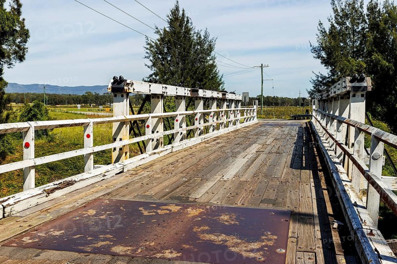Weathered timber decking spans a white trestle bridge in the rural Hunter region, New South Wales, Australia