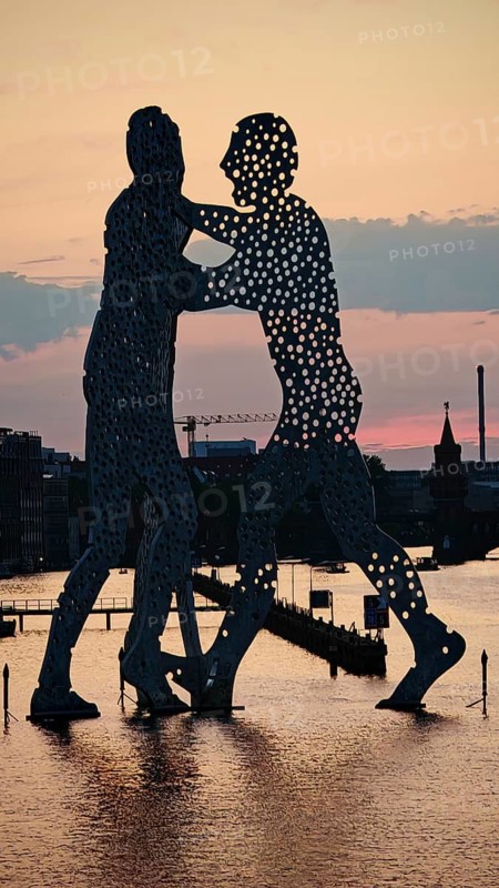 Molecule man, molecule men, sculpture, figures in the water of the Spree against an impressive evening sky and urban environment, sunset, Berlin
