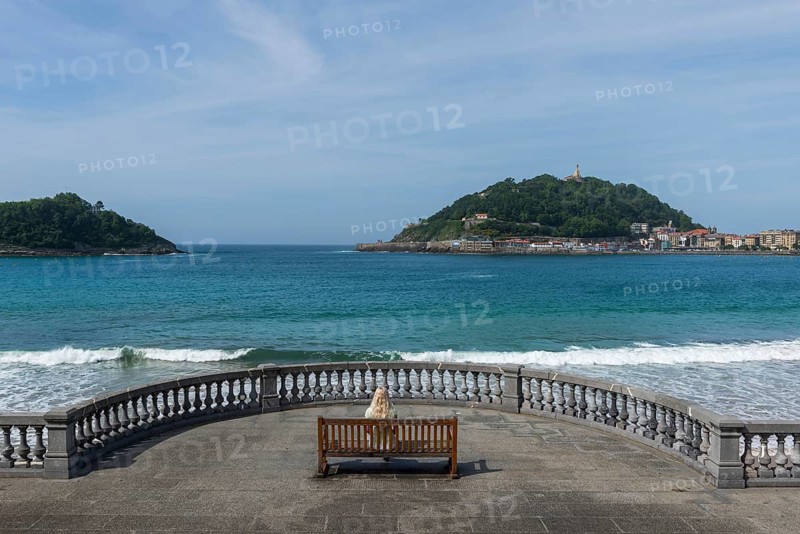 Woman sitting on a bench on the promenade at Bicentennial Balcony, La Concha beach, San Sebastián, Basque Country, Spain