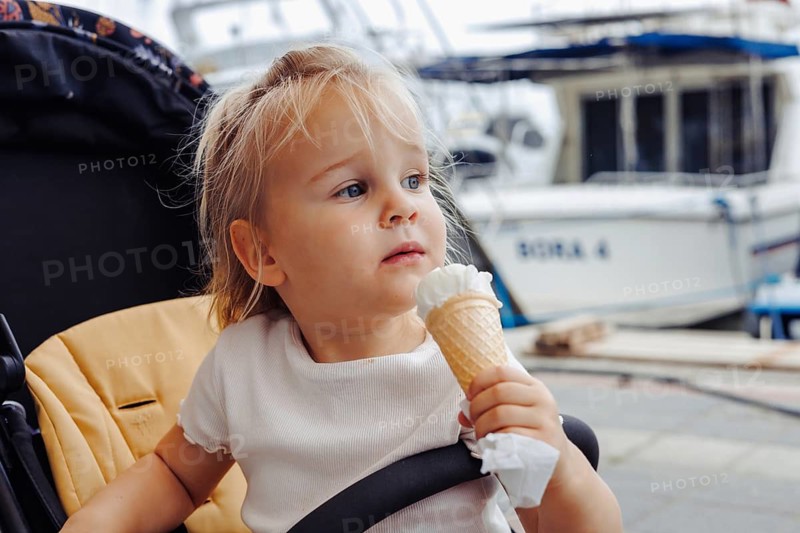 Young girl eating ice cream at a port on a sunny summer day in Fethiye marina, Turkiye