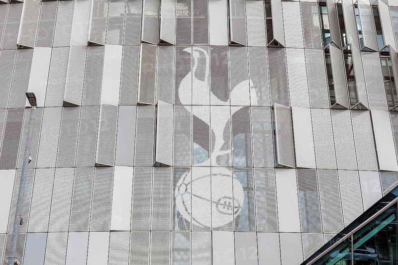 The club's cockerel emblem appears etched across the metallic cladding panels of Tottenham Hotspur Stadium, London, England, United Kingdom