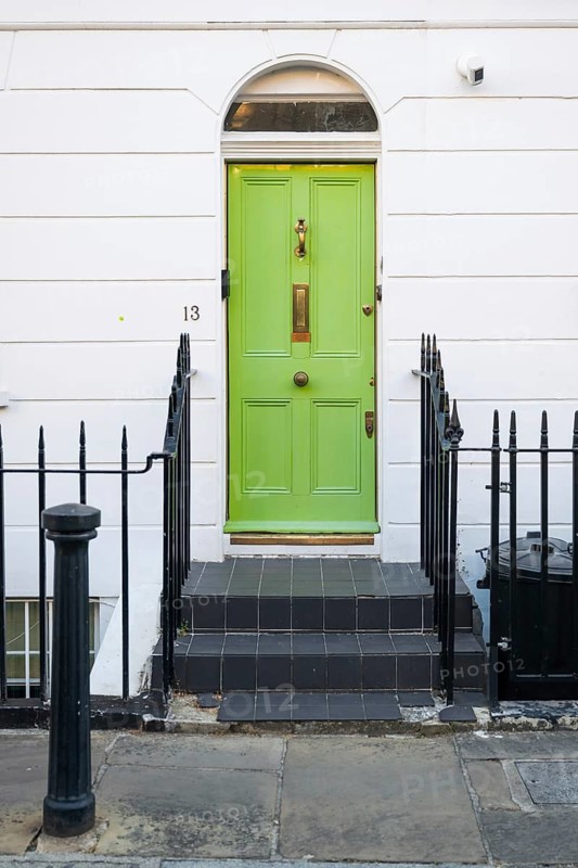 Light green front door with gold fittings in white house facade surrounded by black metal railing, Borough of Chelsea and Kensington, London, England, Great Britain, Great Britain