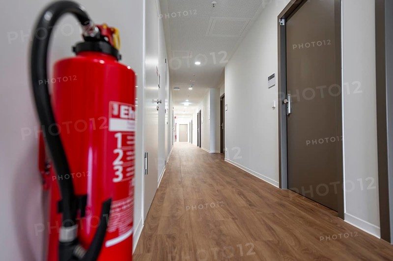 Modern corridor with light wooden floors, fire extinguisher in the foreground and several doors, Boarding House of Klinikverbund Südwest, Böblingen, Germany