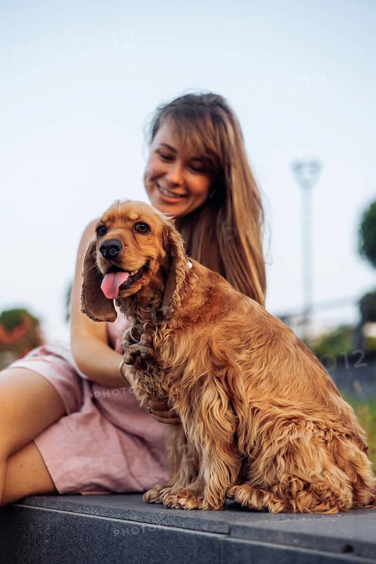 An intimate outdoor moment between a woman and her happy dog in the sun