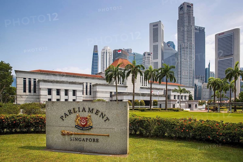 Granite Parliament Singapore marker stands before the grey facade of the legislature building and the financial district skyline, Singapore