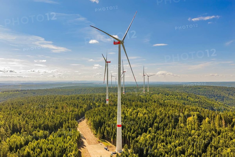 Row of wind turbines standing over an extensive forest under an open blue sky, Besenfeld, Freudenstadt district, Germany