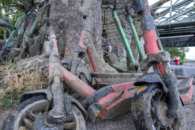 Heavily silted e-bikes and e-scooters recovered from the Rhine show the consequences of improper disposal and the impact on the environment and water, the recovered vehicles were secured on the shore and prepared for proper disposal, Cologne, North Rhine-Westphalia, Germany