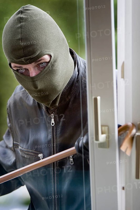 A burglar with a crowbar at a window, studio shot, Austria